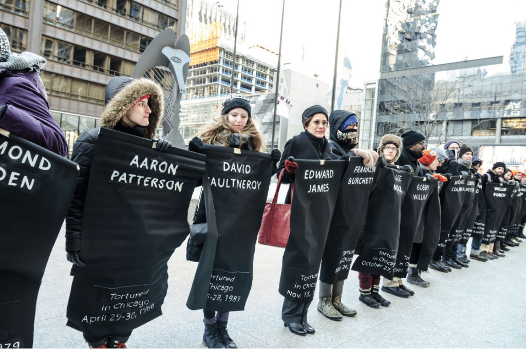 Protestors against Jon Burge hold signs with victims names